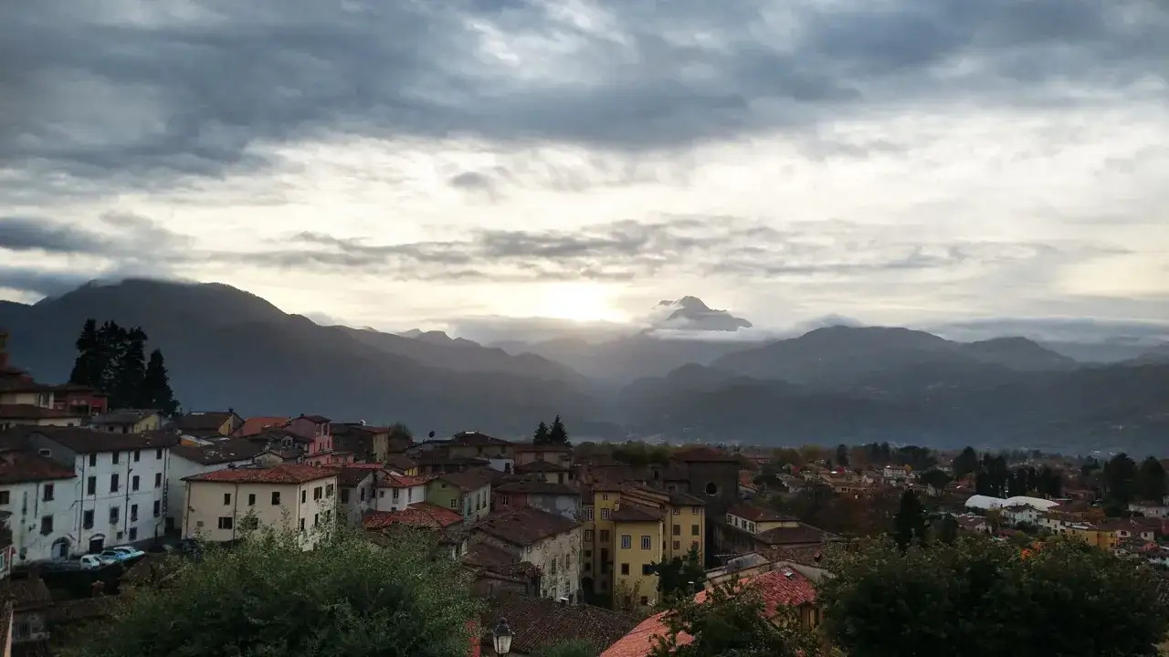 Un borgo toscano con tetti rossi e case colorate, incastonato tra dolci colline e montagne nebbiose. Ecco dove si trova Barga, un gioiello nascosto.