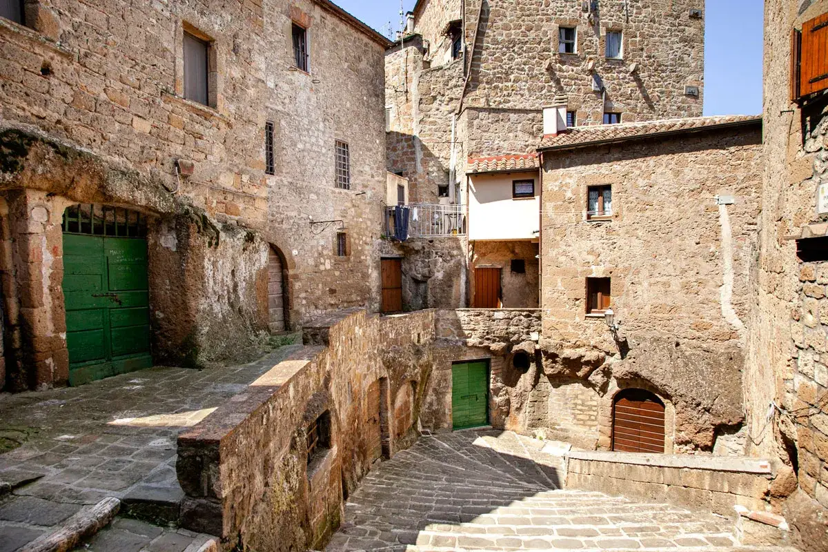 Un vicolo stretto con scale di pietra e case antiche in tufo, un'atmosfera da piccola Gerusalemme.