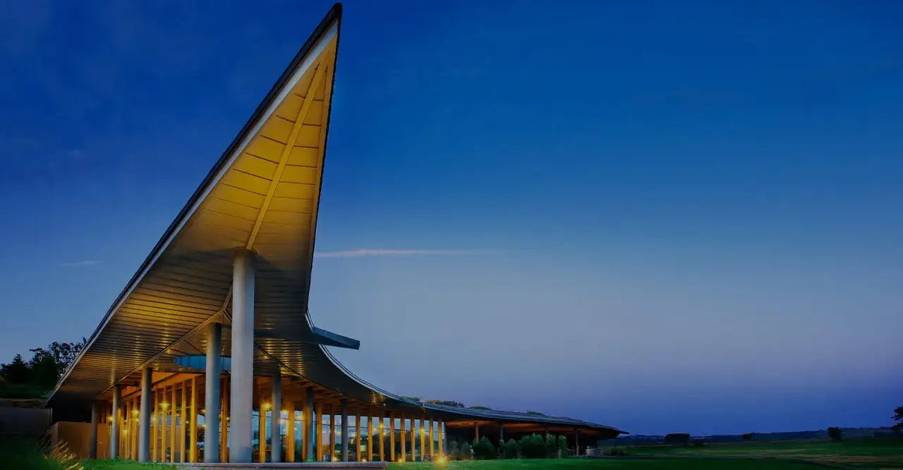 La tenuta ammiraglia Frescobaldi, con la sua architettura moderna e le luci calde, si staglia contro il cielo serale. Le recensioni lodano la sua bellezza.