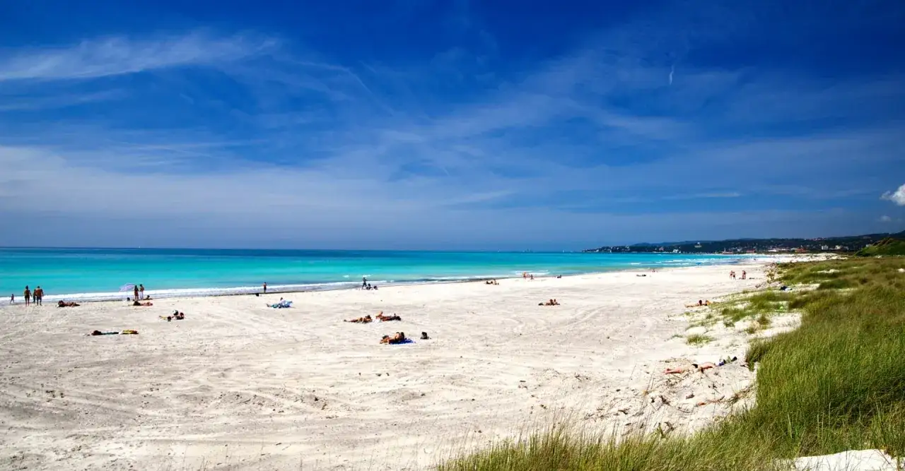 Vada Spiagge Bianche: sabbia chiara, mare turchese e cielo azzurro. Persone rilassate al sole su questa splendida costa.