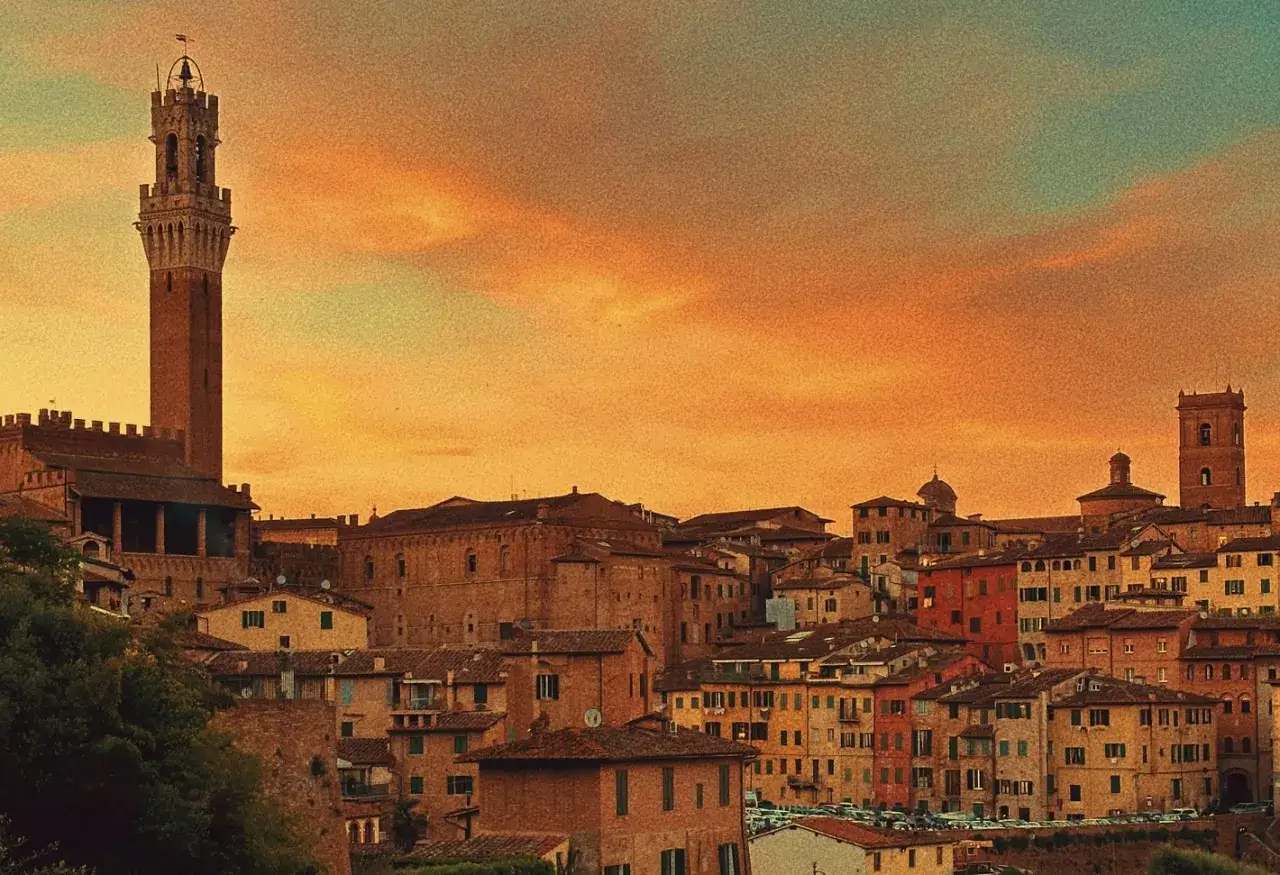 Tramonto infuocato sull'orto dei pecci Siena, con la Torre del Mangia che domina il paesaggio urbano medievale.